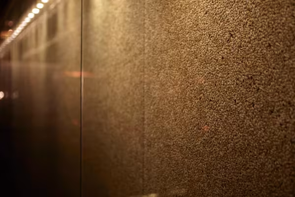 Detalle de una pared de textura granulada dorada iluminada en penumbra en la Johnnie Walker House de Love