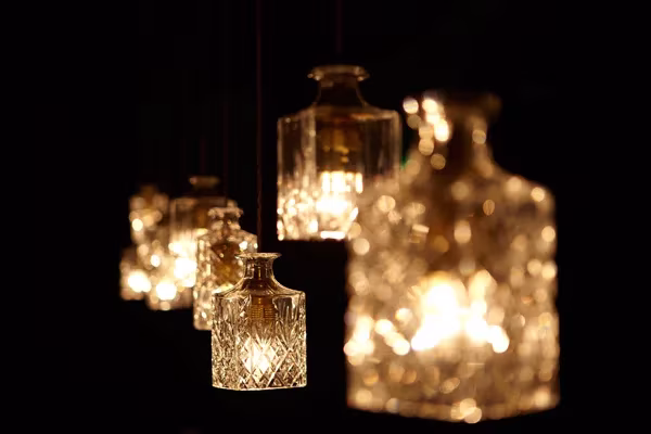 Lámparas colgantes con forma de licorera de cristal tallado encendidas sobre fondo oscuro