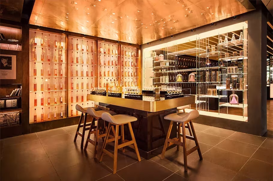 Barra de cata de la Johnnie Walker House por Love con taburetes de madera, techo cobrizo y vitrinas de botellas