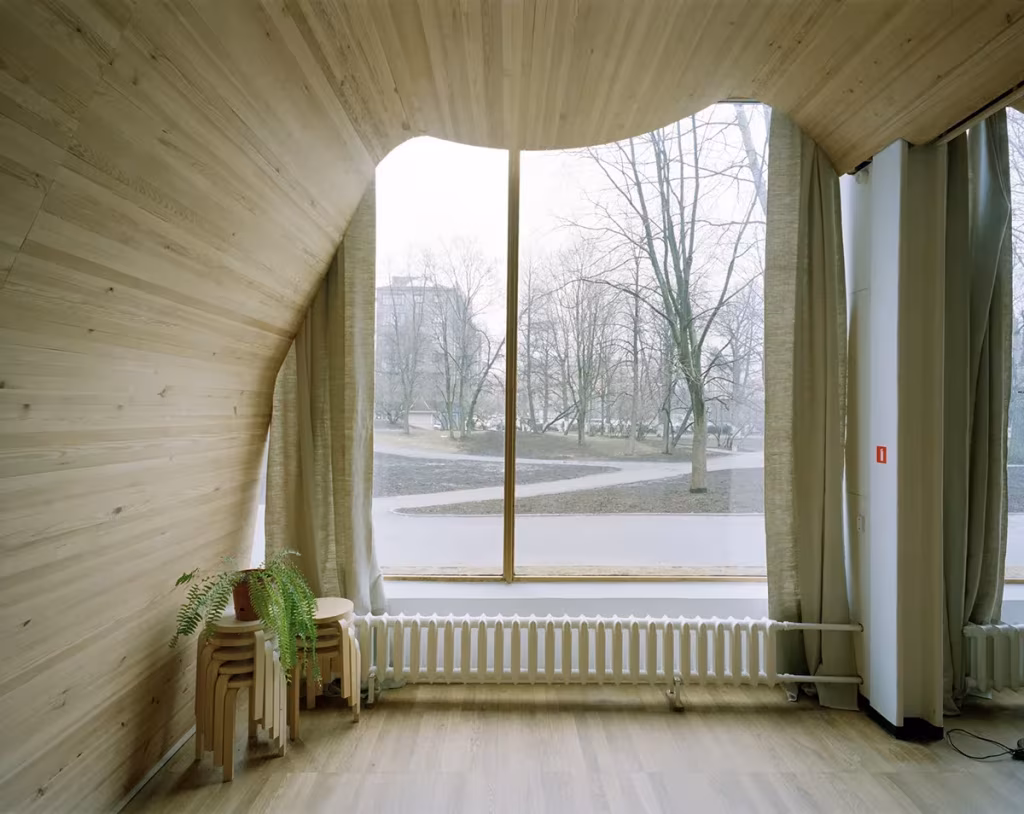 Interior de la Biblioteca de Viipuri de Alvar Aalto con techo ondulado de listones de madera y gran ventanal