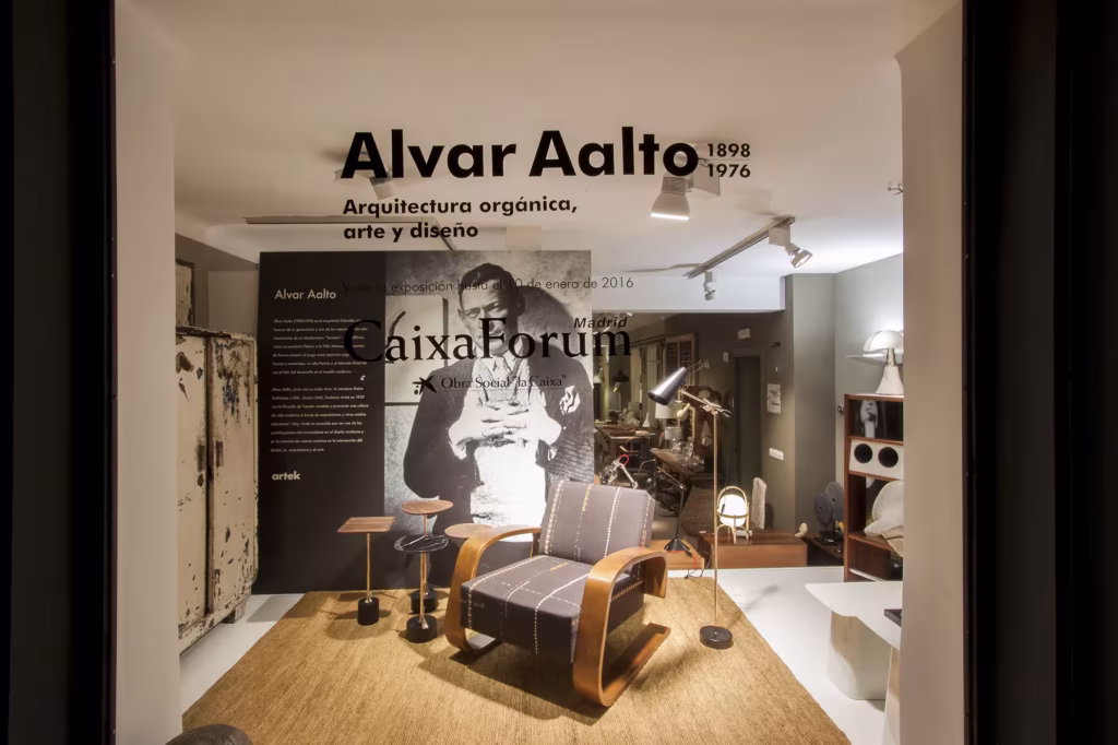 Escaparate de BATAVIA dedicado a Alvar Aalto con una butaca de madera curvada, lámparas y un retrato del arquitecto