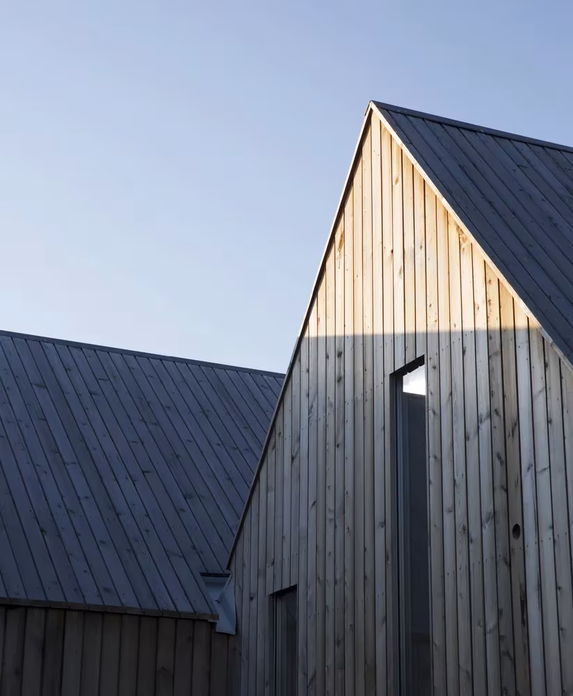 Cabaña de Reiulf Ramstad Arkitekter en Noruega con fachada de listones de madera y cubierta oscura a dos aguas