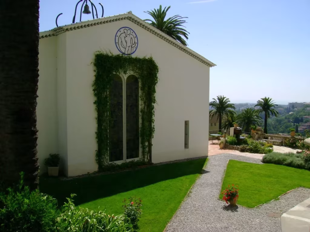 Capilla del Rosario de Henri Matisse en Vence, fachada blanca con vidriera cubierta de hiedra y jardín