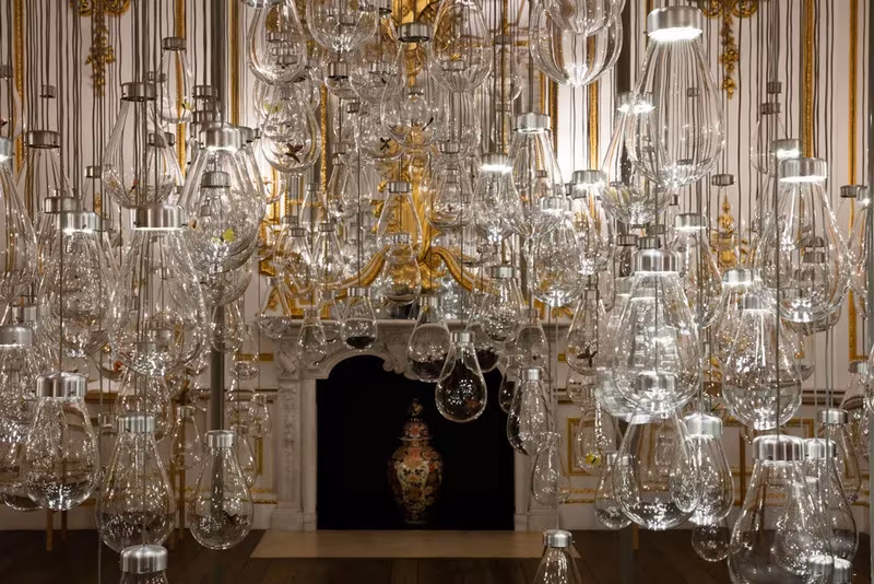 Instalación Curiosity Cloud de Mischer'Traxler con cientos de bombillas de vidrio colgadas en un salón dorado