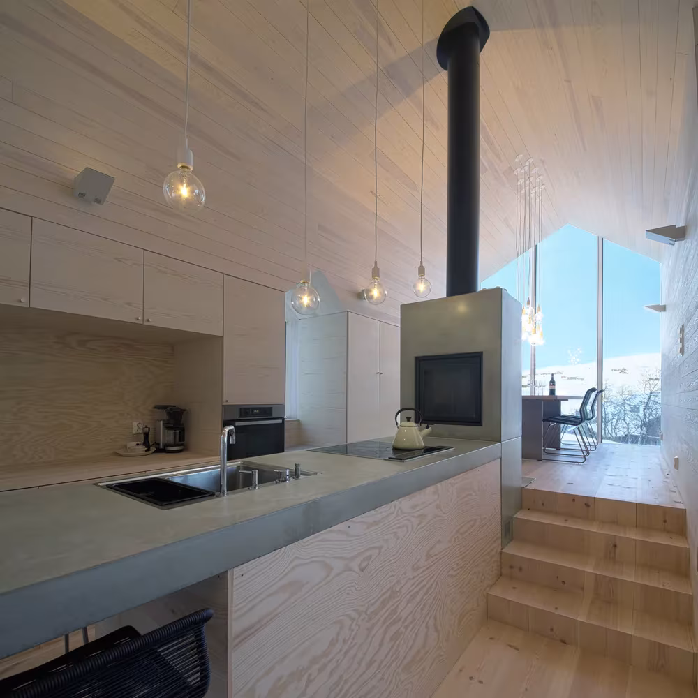 Cocina de madera clara del Split View Mountain Lodge con encimera de hormigón, estufa y escalones