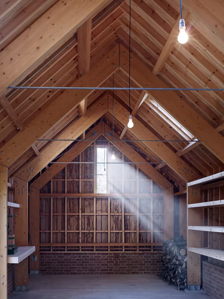 Taller del Long Sutton Studio con cerchas de madera, estanterías y un haz de luz cenital