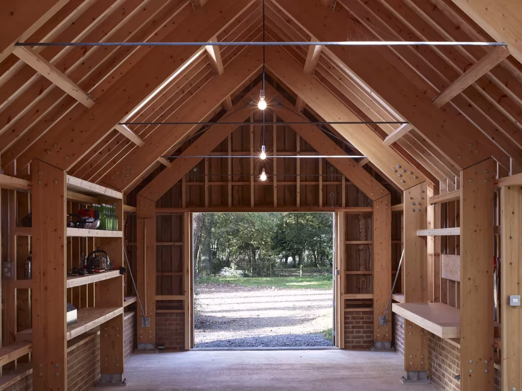 Nave interior del Long Sutton Studio con cerchas de madera, bancos de trabajo y gran puerta abierta