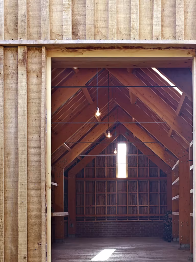 Vista a través del marco de madera hacia la sala a dos aguas del Long Sutton Studio