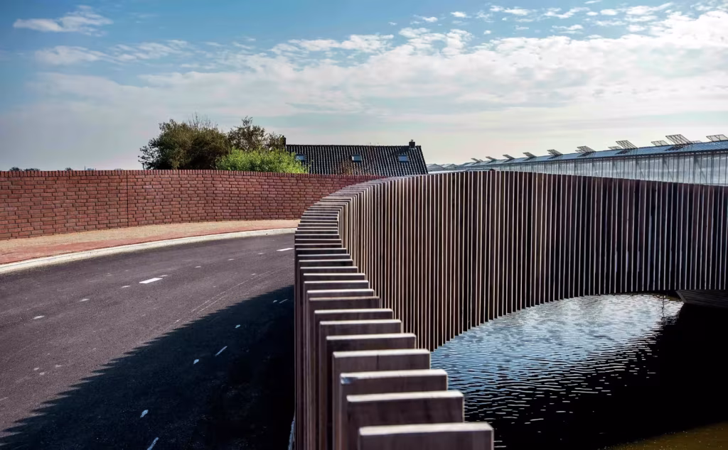 Calzada curva del Vlotwateringbrug con muro de ladrillo y barandilla de listones de madera sobre el agua