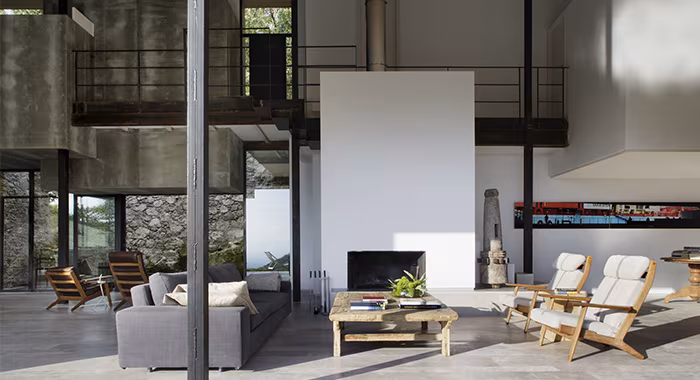 Salón de doble altura en un antiguo establo rehabilitado por ÁBATON, con chimenea blanca, sofás y pasarela metálica