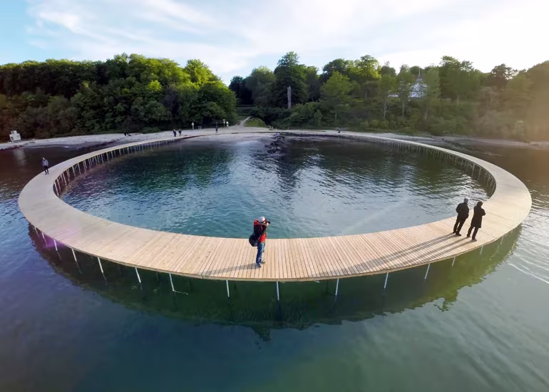Puente circular de madera de Gjøde & Povlsgaard en Aarhus sobre el mar con personas paseando