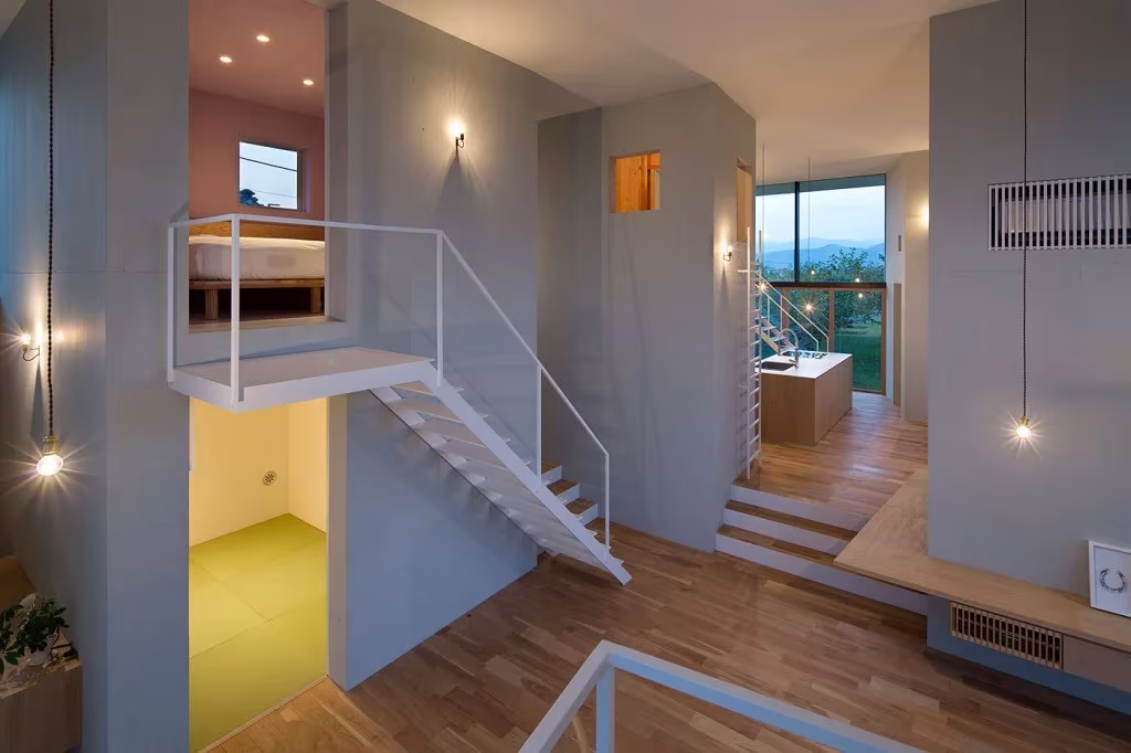 Interior de la casa Ohno con escaleras blancas de acero, altillos, suelo de madera y luces colgantes