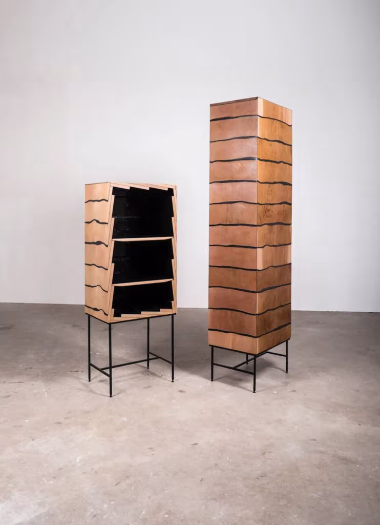 Mueble Fuse abierto de cedro y resina negra junto a una columna cerrada de madera en el estudio