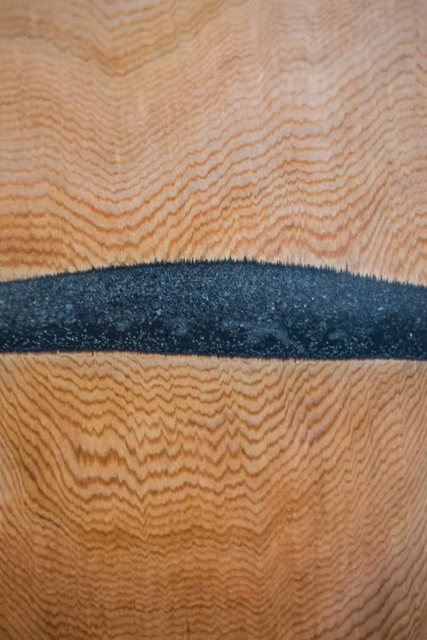 Detalle macro de una franja de resina de mármol negro entre dos piezas de cedro de vetas marcadas