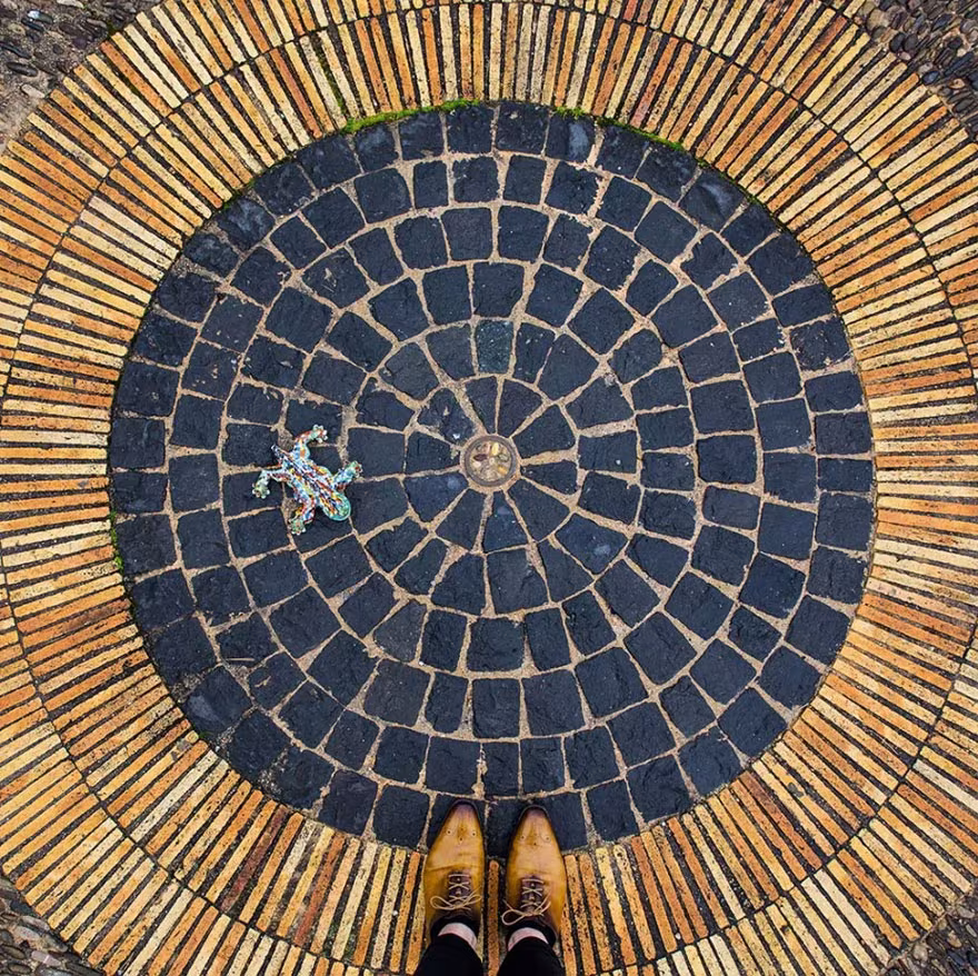 Pavimento circular de piezas azul oscuro rodeado de anillos dorados con zapatos marrones al borde