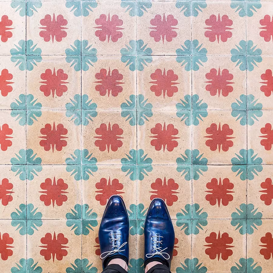 Baldosas claras con tréboles rojos y turquesa alternados y zapatos azules en el borde inferior