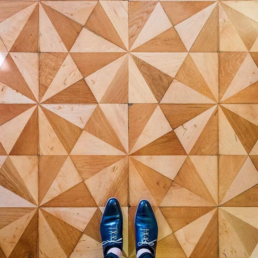 Parqué de madera con triángulos claros y oscuros que forman estrellas, con zapatos azules encima