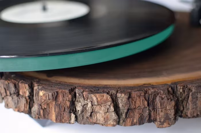 Primer plano de un vinilo sobre plato de vidrio y la corteza de la base de madera del tocadiscos
