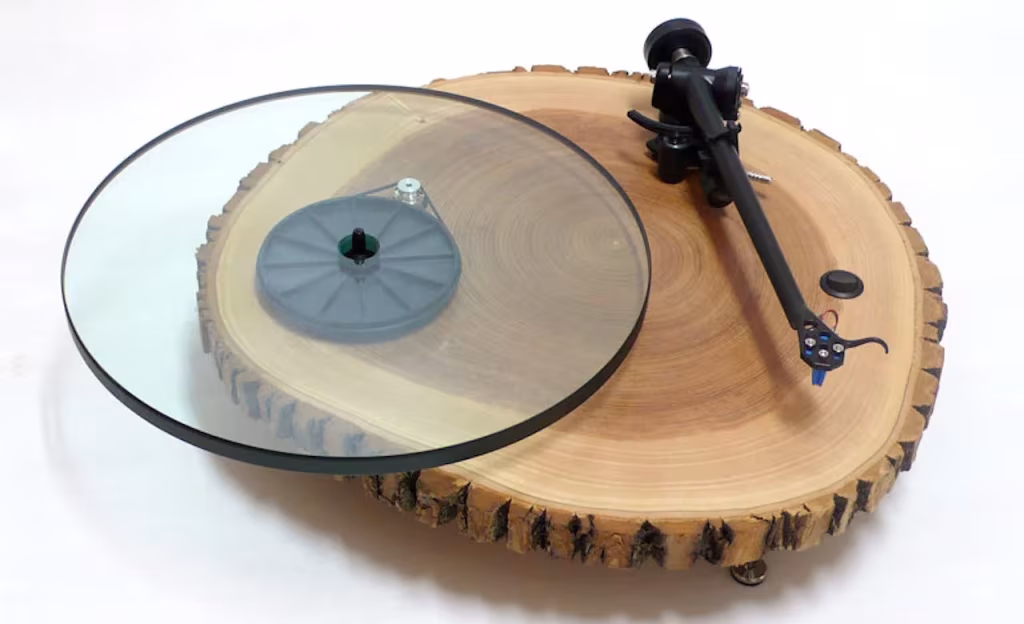 Tocadiscos de Silvan Audio Works con plato de vidrio sobre una rodaja clara de tronco con sus anillos visibles
