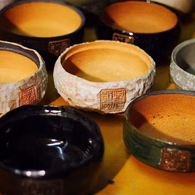 Cuencos de cerámica japonesa artesanal con esmaltes oscuros y sellos grabados