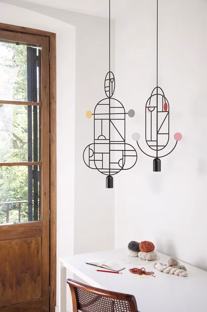Lámparas Lines & Dots colgadas junto a una ventana de madera sobre un escritorio blanco con ovillos