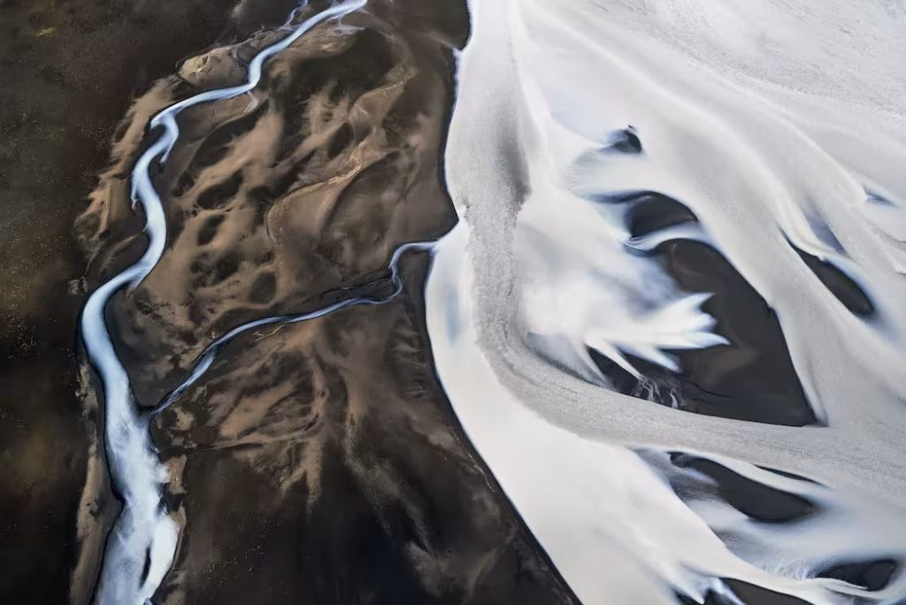 Fotografía aérea de Daniel Beltrá de un río serpenteante entre sedimentos claros y oscuros en Islandia