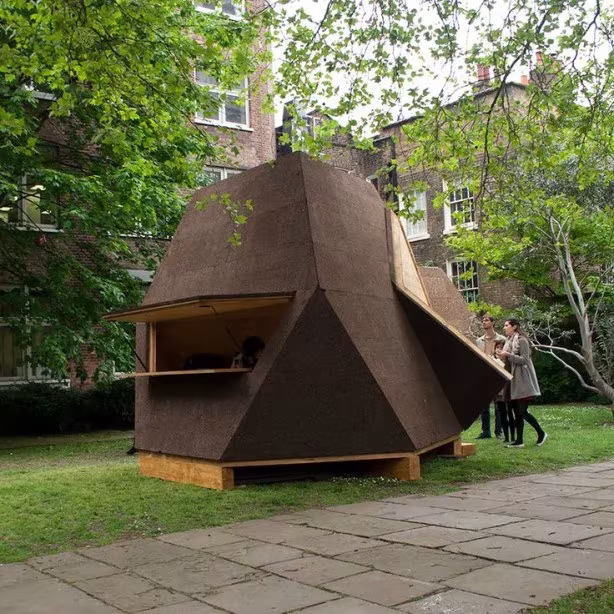 Prototipo de Tetra Shed revestido de corcho en un jardín urbano junto a visitantes