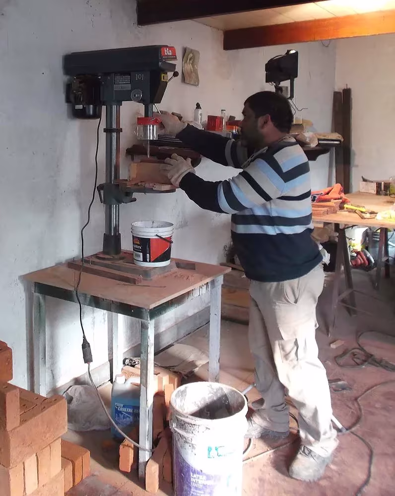 Operario taladrando ladrillos en un taller para montar los paneles de celosía del pabellón