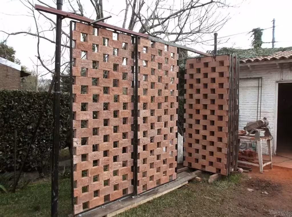 Paneles de celosía de ladrillo terminados apoyados en un patio durante la construcción del pabellón