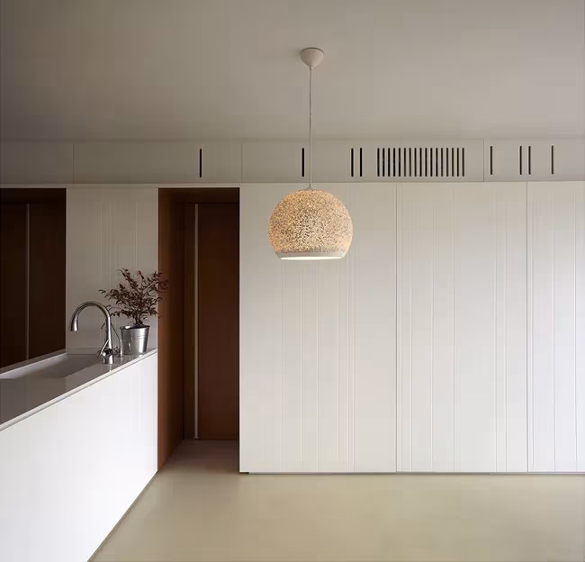 Cocina de la Casa BHMM con encimera blanca, lámpara colgante de fibra y armarios integrados