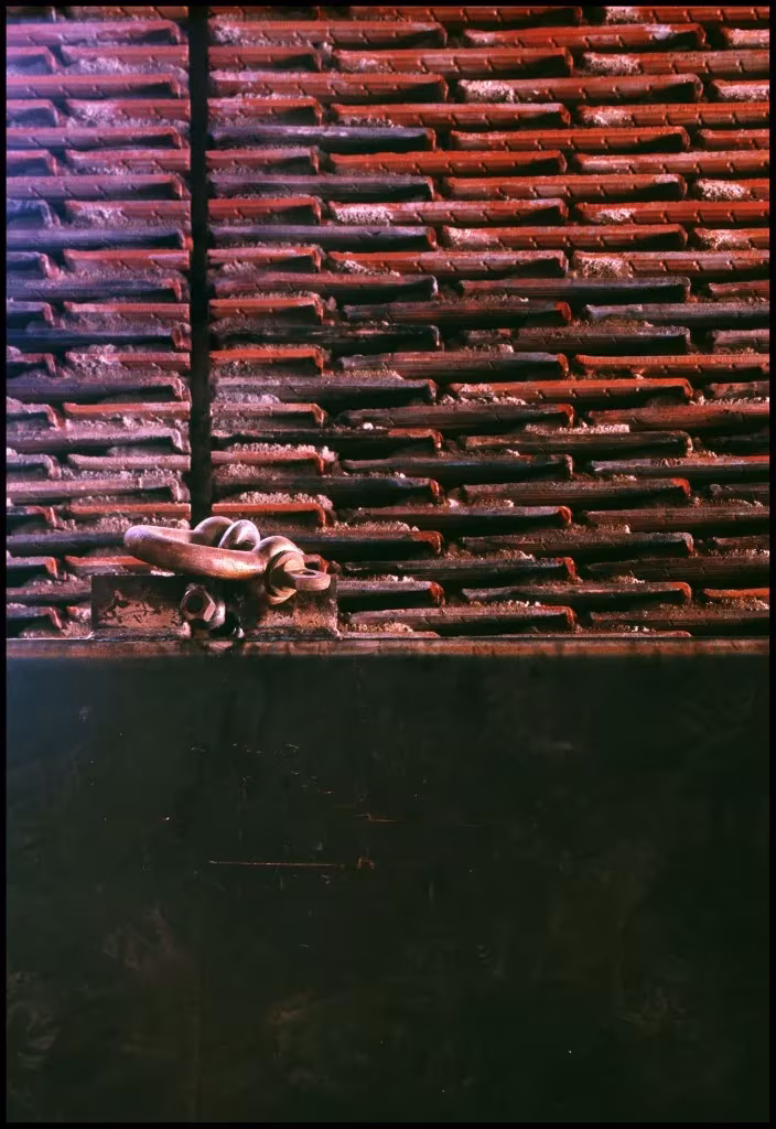 Muro de tejas apiladas sobre un zócalo oscuro con un tirador metálico en la nave 8B del Matadero