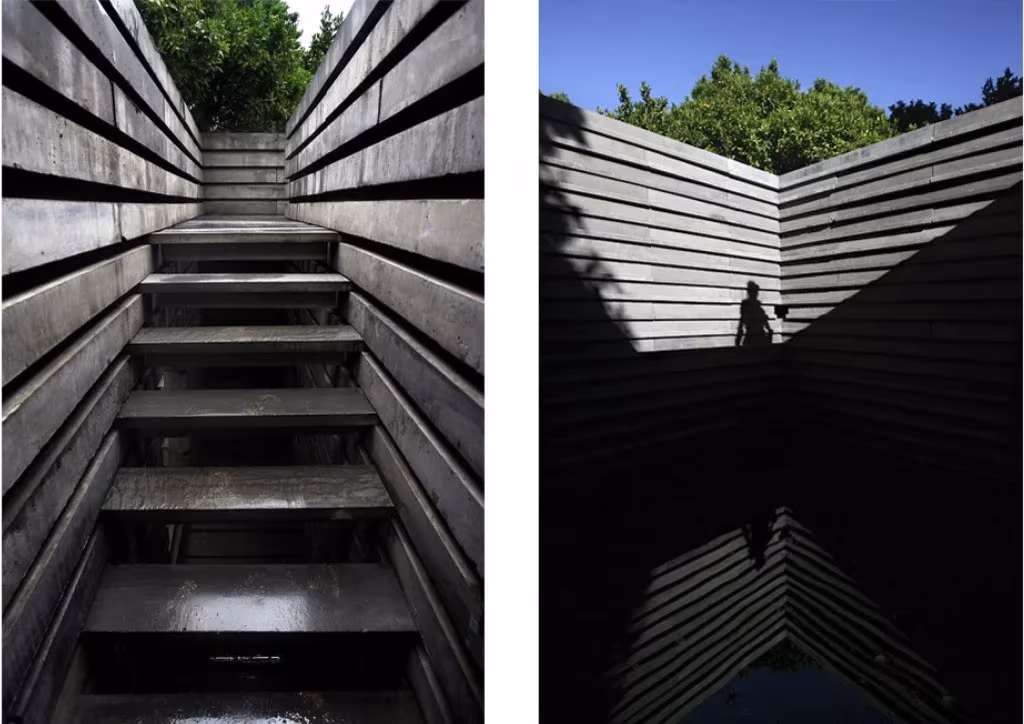 Escalera entre muros de hormigón apilado y vista del cielo desde el patio del pabellón Kairos