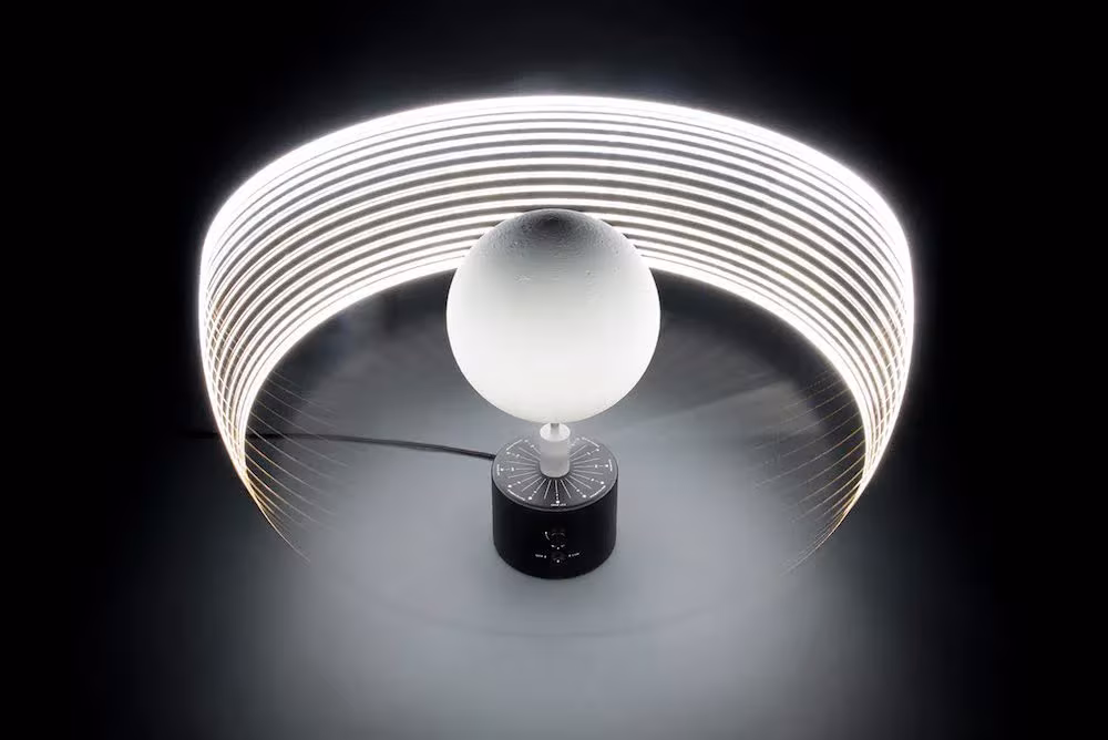 Esfera lunar MOON de Oscar Lhermitte iluminada sobre su base, rodeada por un anillo de luz