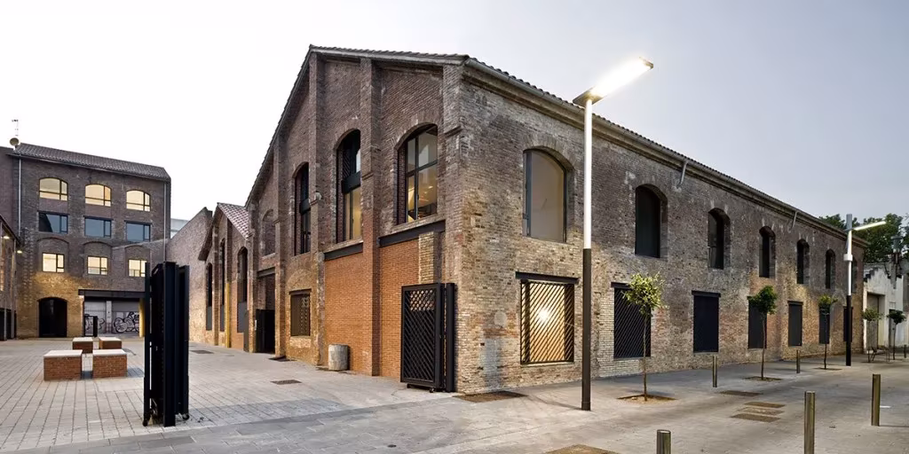 Nave de ladrillo con cubierta a dos aguas en la calle peatonal de los lofts del Poblenou al atardecer