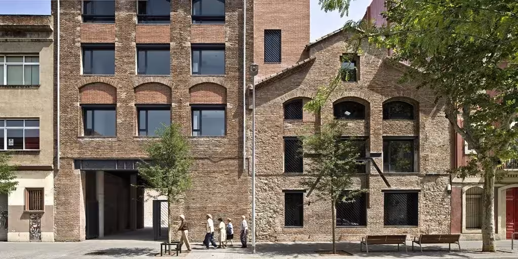 Edificios de ladrillo de la antigua destilería del Poblenou vistos desde la calle arbolada