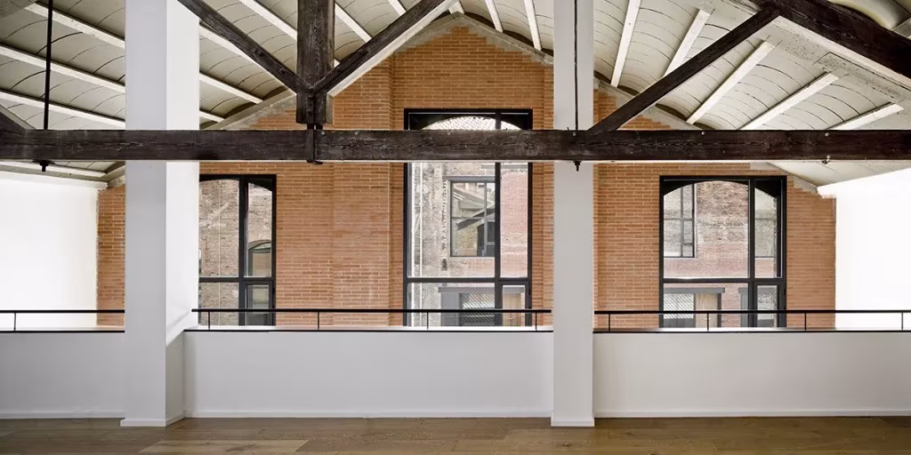 Imagen interior del loft de Garcés De Seta Bonet en Barcelona. Cercha de madera Interior blanco de un loft del Poblenou con cerchas de madera y hastial de ladrillo con ventanas en arco