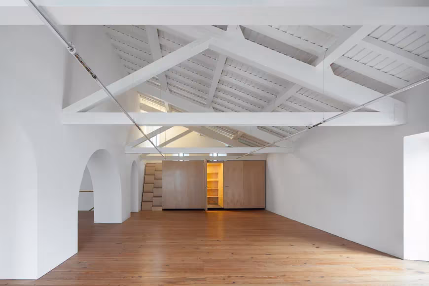 Sala blanca del centro Arquipélago en las Azores con suelo de madera y cerchas pintadas de blanco