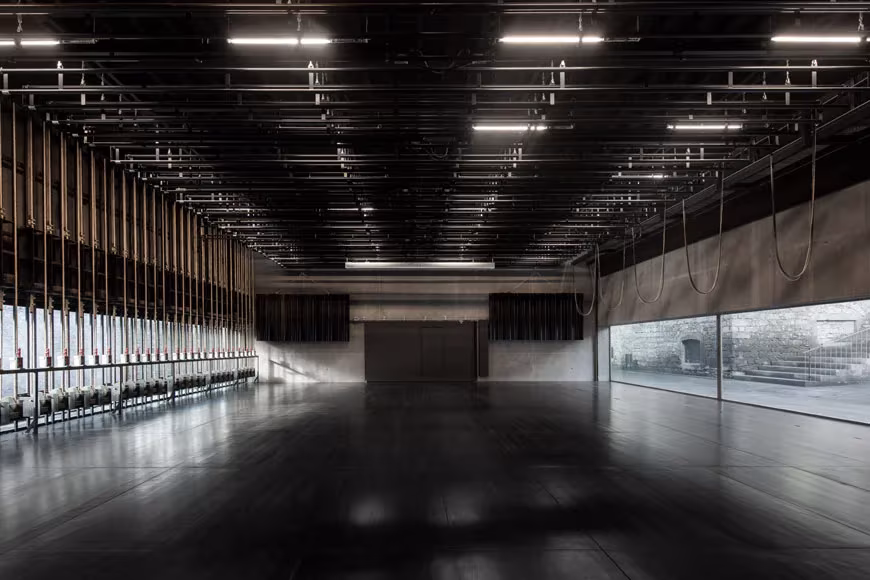 Nave de exposiciones del centro Arquipélago con suelo pulido, techo técnico negro y ventanal corrido