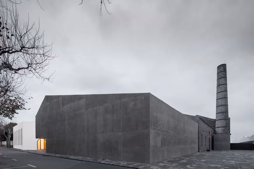 Bloque de hormigón gris del centro Arquipélago con la chimenea de la antigua fábrica de tabaco detrás