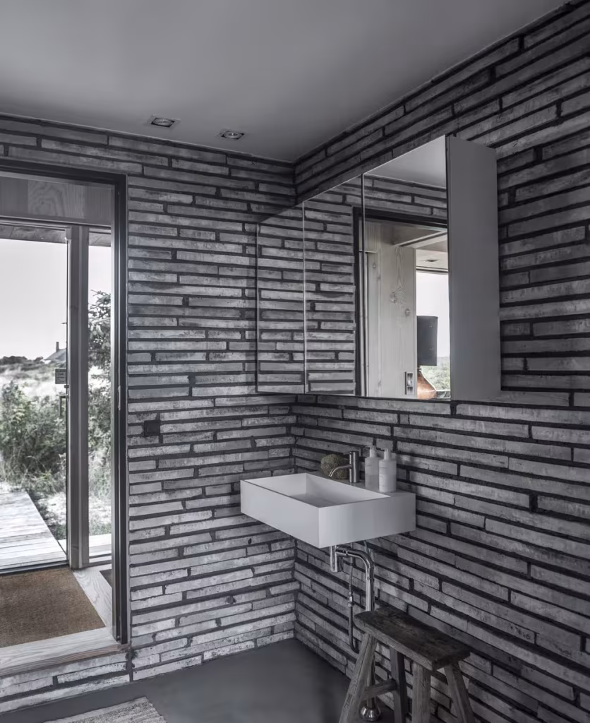 Baño de la Summer Cottage G18 con paredes de listones de madera, lavabo blanco y espejo