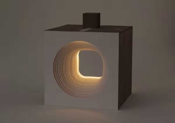 Lámpara cubo Panta Rei encendida, con capas de madera que forman un hueco circular iluminado