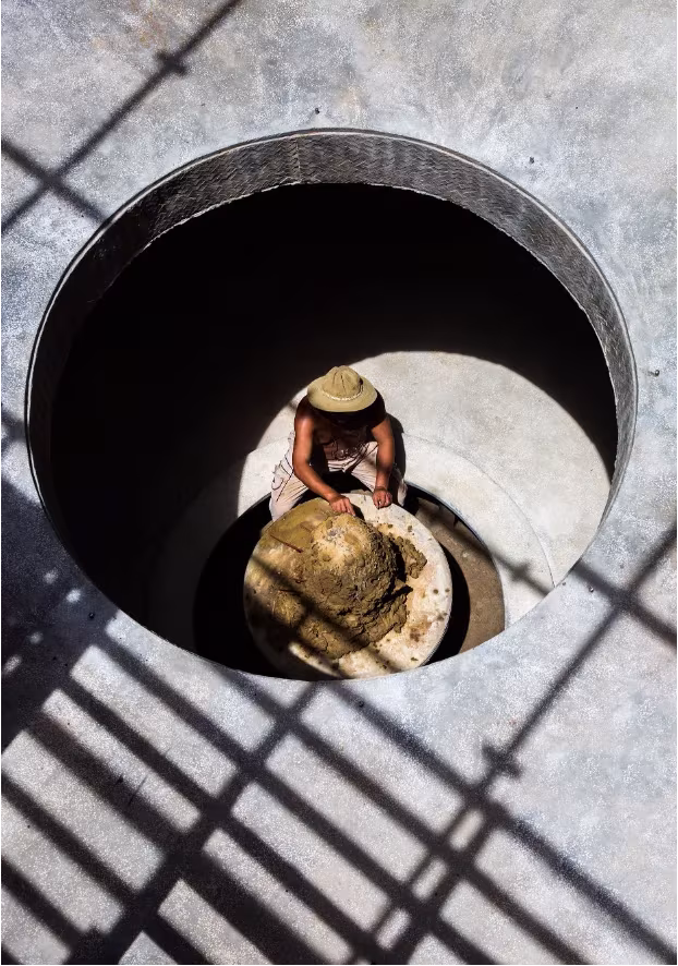 Alfarero trabajando en el torno dentro del pozo circular del Terra Cotta Studio, visto desde arriba