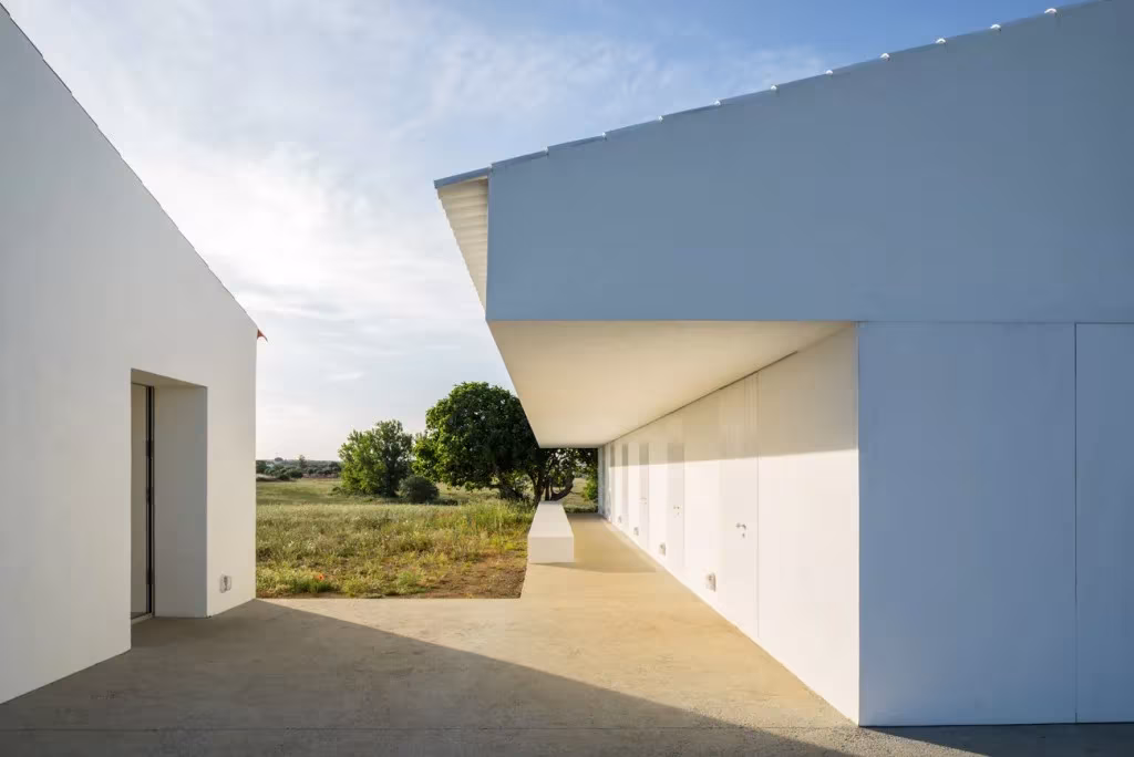 Porche de Monte da Azarujinha bajo un gran voladizo blanco, con fila de puertas a las habitaciones