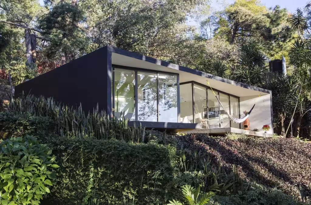 Fachada acristalada del Bungalow LMM en Tepoztlán con hamaca interior, entre vegetación tropical