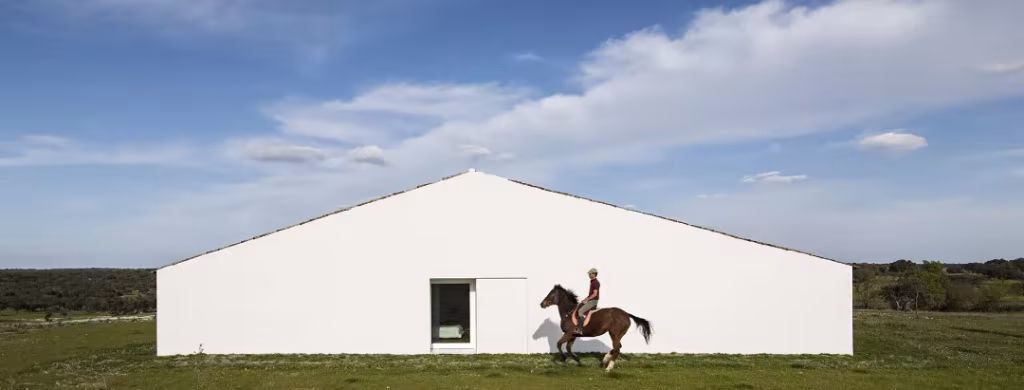 Hastial blanco de Casa no Tempo con un jinete a caballo delante, en el campo alentejano