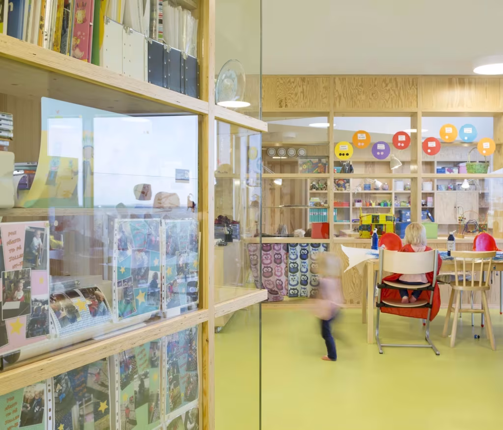 Dorte Mandrup. Guardería infantil Råå. Interior Mamparas de vidrio y estanterías con libros y material escolar en la Guardería Råå
