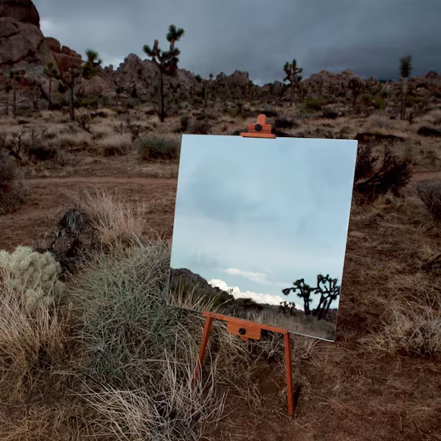 Espejo en caballete sobre el desierto de Joshua Tree reflejando el cielo y árboles de Josué
