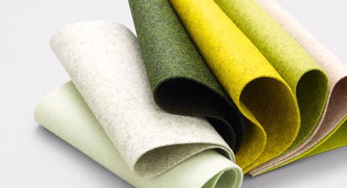 Muestras de fieltro de lana en tonos verdes, amarillos y crema enrolladas