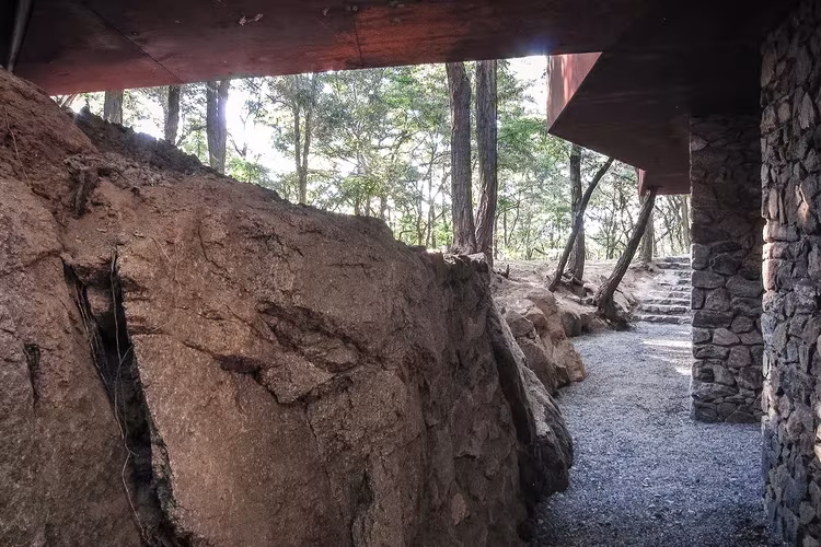 Estudio TAO (Trace Architecture Office). Rockview Teahouse, situada en el Parque Tashan, Roca de la cantera junto al voladizo de la Rockview Teahouse y un camino de grava entre pinos