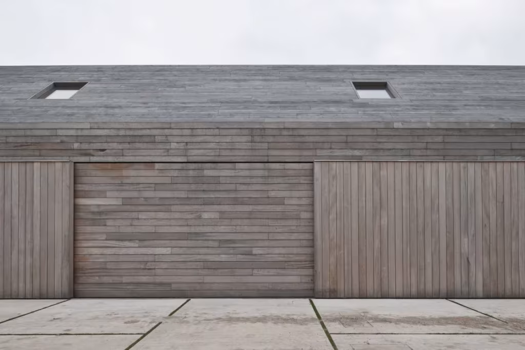 Fachada de la Casa DC II con panel central de tablas horizontales entre dos puertas de lamas verticales